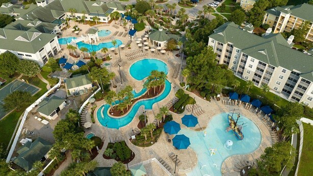 An aerial view of a resort with multiple swimming pools, lounge areas, and a large building complex.