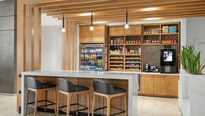 Un área de bar moderna con encimera de mármol, taburetes de madera y una selección de bebidas y aperitivos.