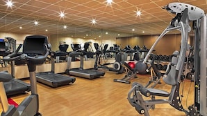 Un gimnasio con cintas de correr, elípticas y equipo de levantamiento de pesas.
