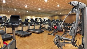Un gimnasio con cintas de correr, elípticas y equipo de levantamiento de pesas.