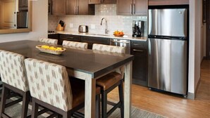 Una cocina moderna con armarios de madera oscura, un refrigerador de acero inoxidable, una isla grande con taburetes de bar e iluminación colgante.