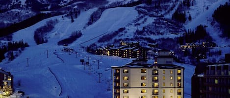 Une montagne enneigée, avec une station de ski et un hôtel à plusieurs étages doté de balcons.