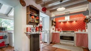 A kitchen with a red brick backsplash, a built-in oven, and a hanging pot rack. - El Jardín Escondido - country house in Helgueras (Cantabria) | 12 guests (Helgueras)