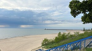 A beach with a blue metal staircase leading down to the shore, a pier extending into the water, and a cloudy sky. - 5 O'clock Somewhere - large home, hot tub & close to the beach! (South Haven)