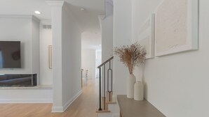 A modern interior with a staircase, a flat-screen TV, and minimalist decor. - 5 O'clock Somewhere - large home, hot tub & close to the beach! (South Haven)