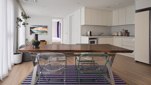 Una cocina moderna con armarios blancos, una isla de madera y una zona de comedor con sillas traslúcidas.