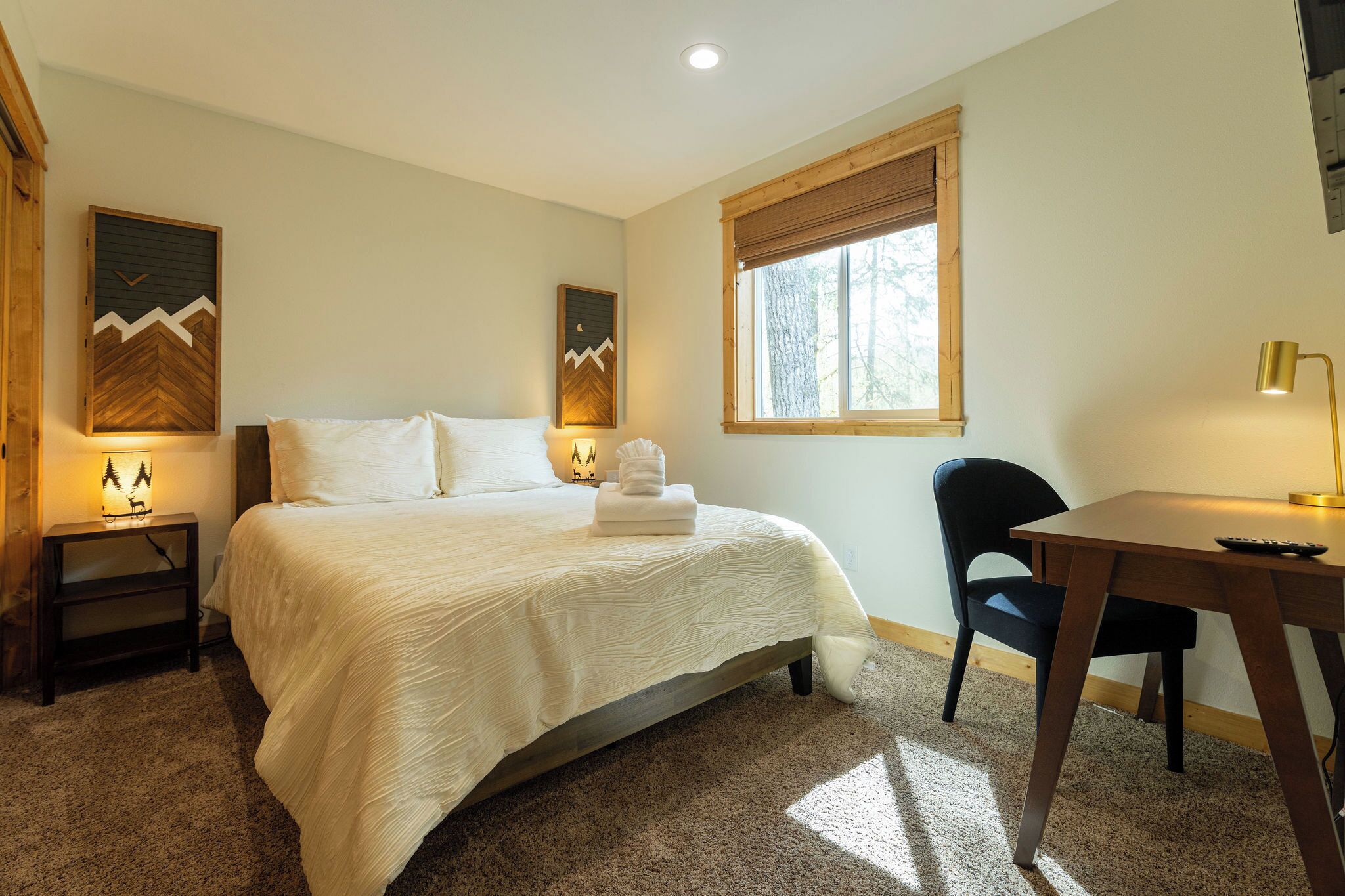 A bedroom with a bed, bedside tables, a desk, and a chair.