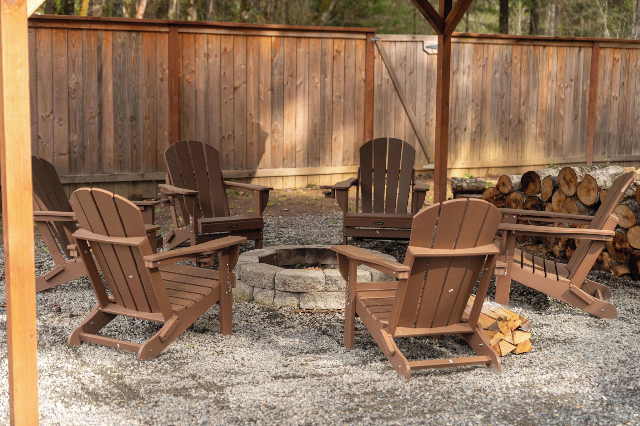Une terrasse en bois avec des fauteuils Adirondack, un foyer et une table.