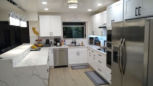 A modern kitchen with white cabinets, stainless steel appliances, and a marble countertop. - Sleeps 50+ NEW Luxury Private Resort with Pool Golf Arcade Spa Playground Poker (Lakeside)