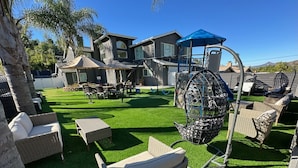 A backyard with artificial grass, wicker furniture, and a swing set. - Sleeps 50+ NEW Luxury Private Resort with Pool Golf Arcade Spa Playground Poker (Lakeside)
