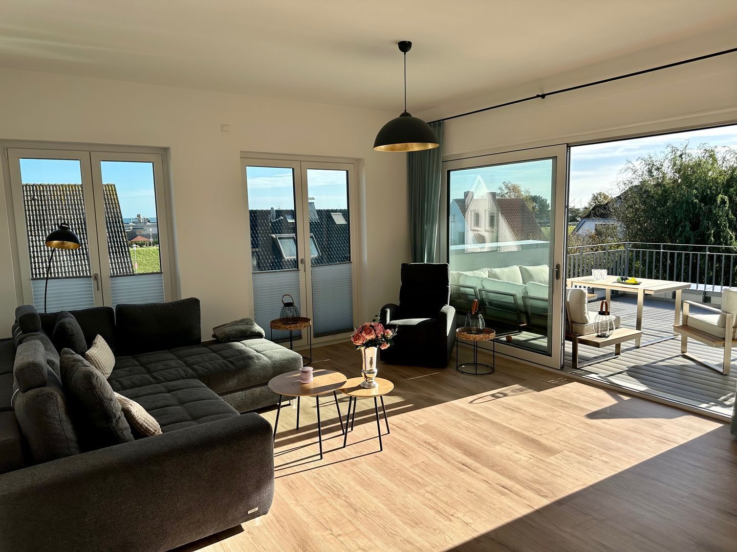Amplia sala de estar con un sofá grande, una mesa de centro y un balcón con mobiliario exterior.