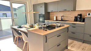 Eine moderne Küche mit grauen Schränken, einer Holz Arbeitsplatte und einem eingebauten Herd.