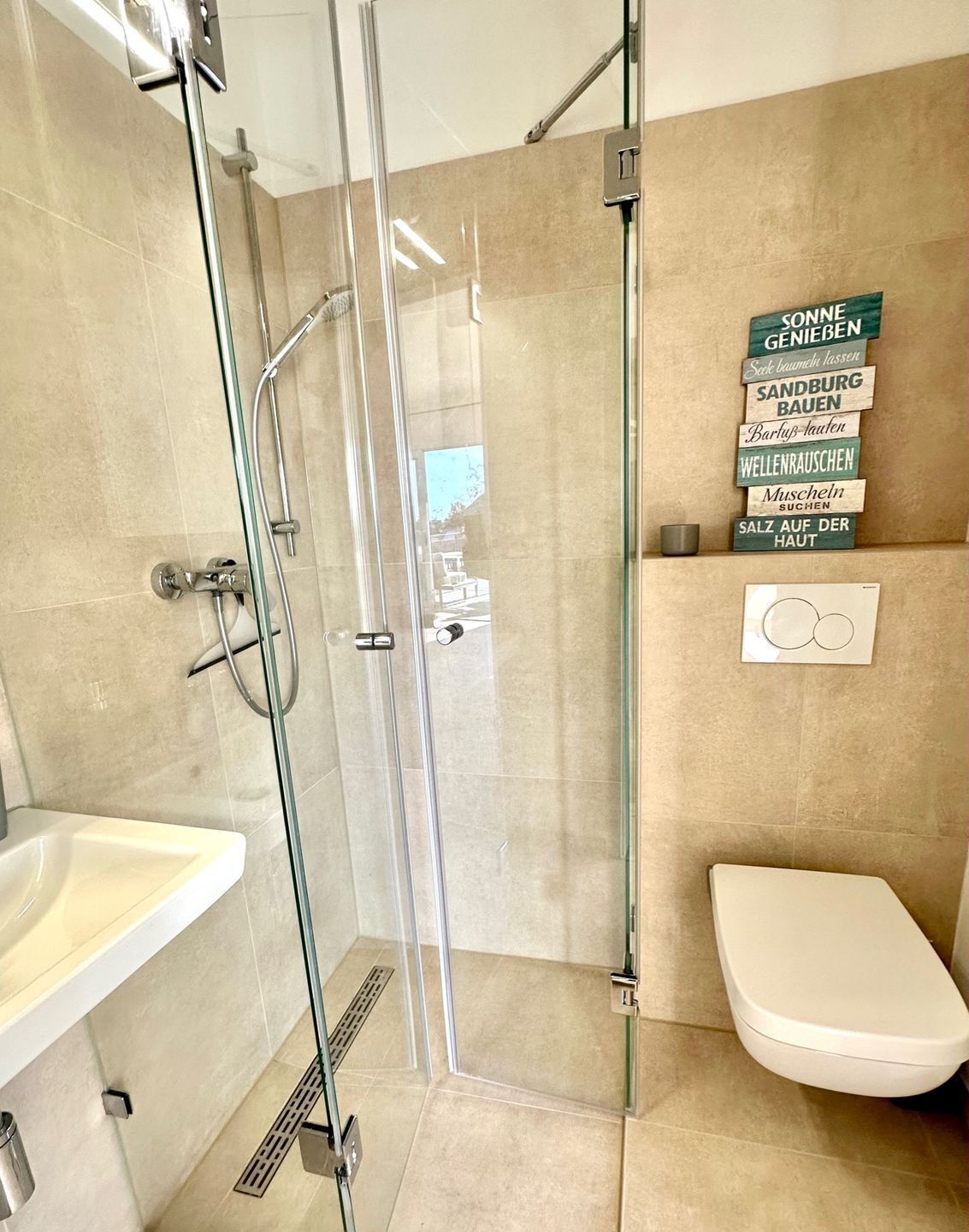 Une salle de bain moderne avec une douche à parois de verre, un lavabo blanc et des toilettes.
