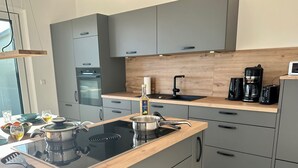 Eine moderne Küche mit einem schwarzen Induktionskochfeld, einer Holz Arbeitsplatte und grauen Schränken.