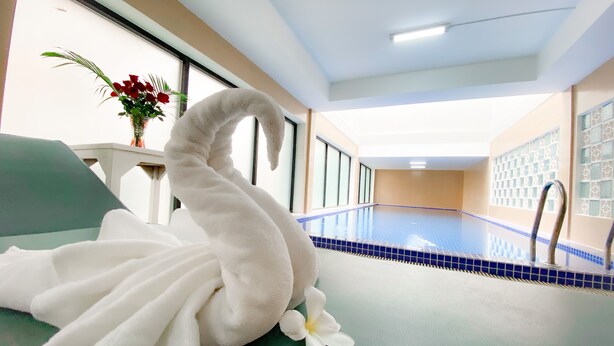 A swimming pool with a white towel shaped like a swan and a white flower on a green surface. - ANGKOR SIVUTHA HOTEL (Siem Reap)