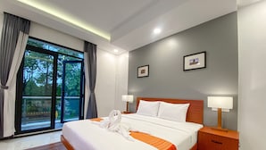 A hotel room with a large bed, two bedside tables, a window with curtains, and a view of greenery outside. - ANGKOR SIVUTHA HOTEL (Siem Reap)