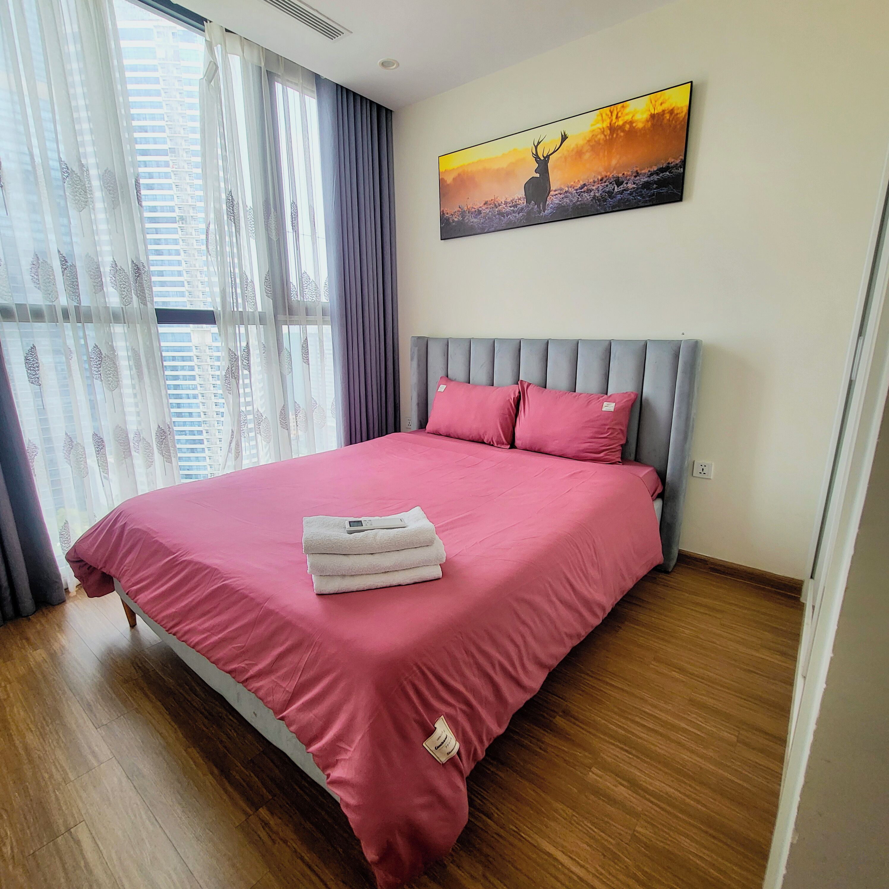 Ein Schlafzimmer mit Bett, einem Vorhangfenster, einem Bild an der Wand und einem Holzboden.