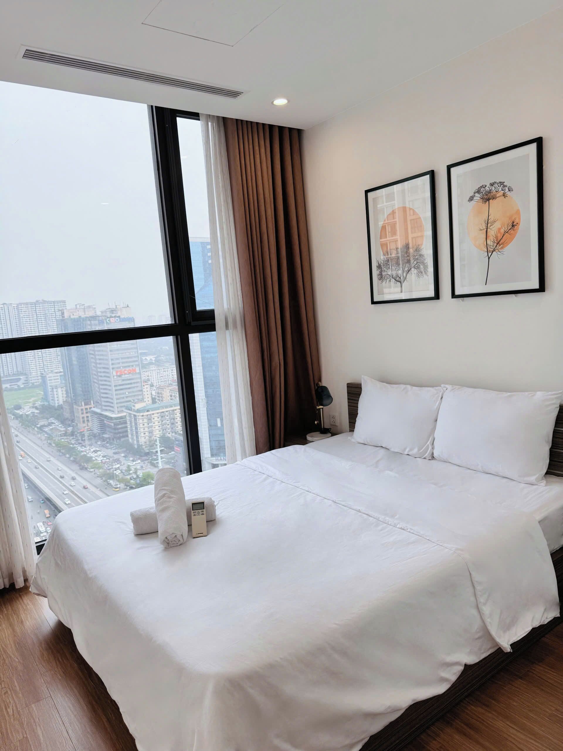 A hotel room with a large bed, a nightstand, a lamp, and two framed pictures on the wall.