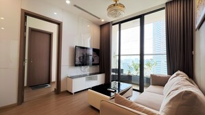 Un salon moderne comprenant un canapé, une table basse, un téléviseur fixé au mur et une porte donnant sur une autre pièce.
