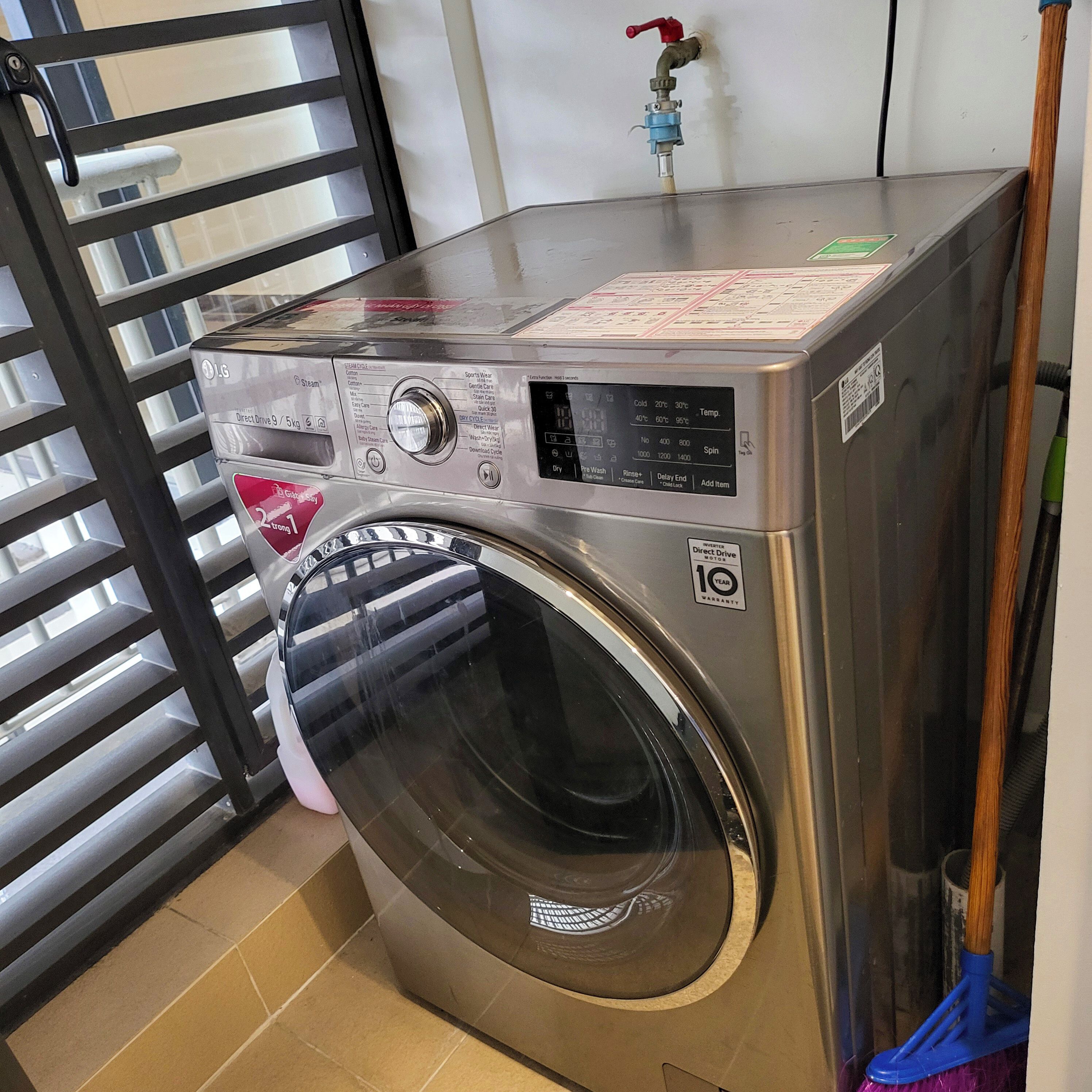A front-loading LG direct drive washing machine with a 10-year warranty, located in a laundry room with a tiled floor and a metal rack.
