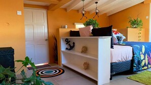 A bedroom with a bed, a white dresser, a shelf with decorative items, and a door. - Story Villa, 2 Bedrooms with Mountain & Ocean View (Canaries)