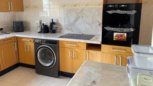 A kitchen with a washing machine, a coffee maker, a blender, a refrigerator, and a microwave. - 3 Bed House - Sleeps 9 - Pets - Garden - Parking (Accra)