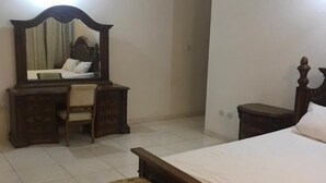 A bedroom with a bed, a wooden bench, a desk with a chair, and a mirror. - 3 Bed House - Sleeps 9 - Pets - Garden - Parking (Accra)