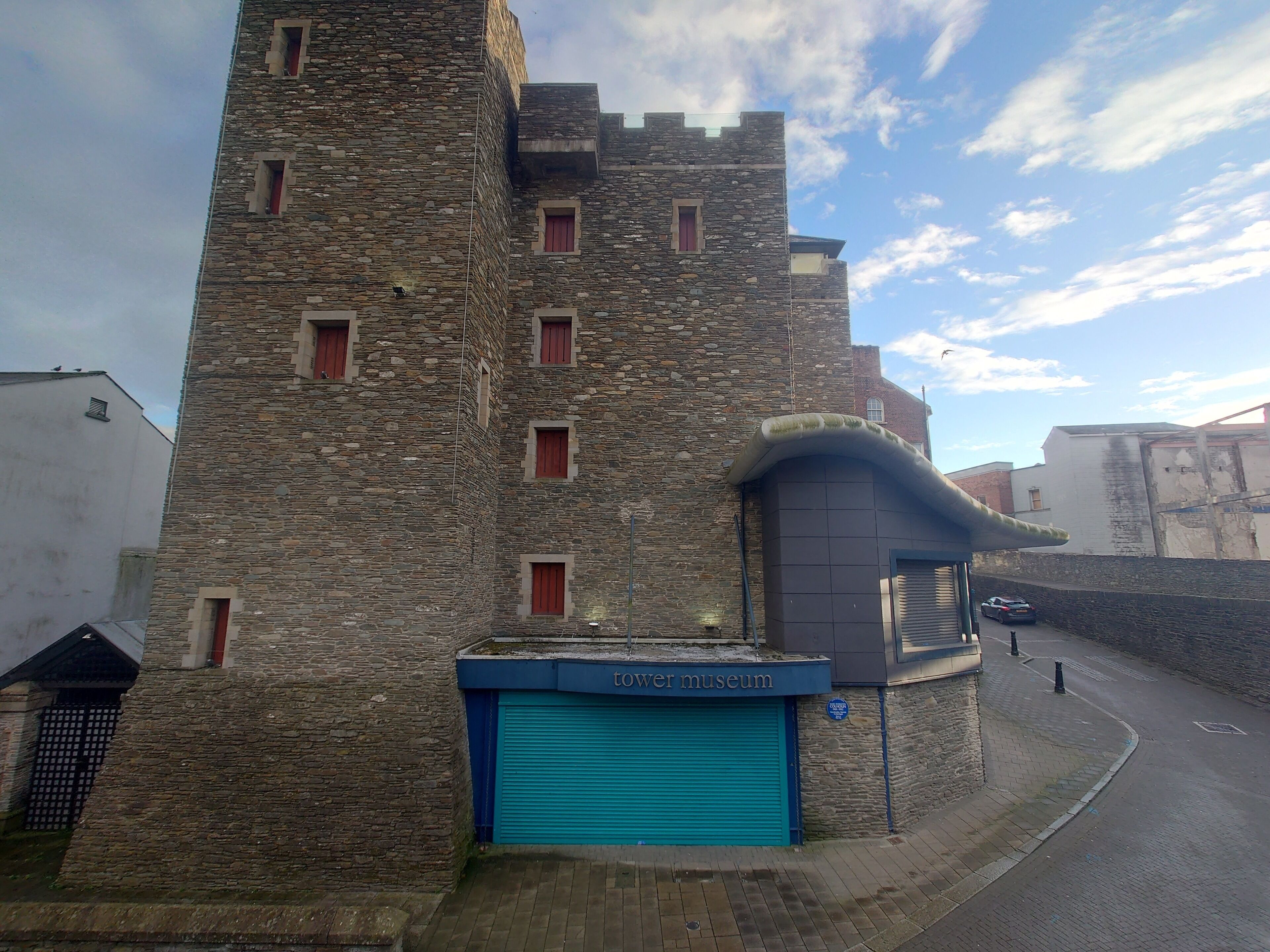 A stone building with a blue garage door labeled "tower museum."