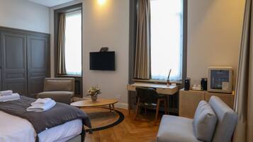 Una camera d'albergo con un letto, una scrivania, una sedia, una televisione e una macchina del caffè.