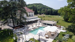 Un edificio spazioso con piscina, area salotto esterna e vista su una collina ricoperta di alberi.