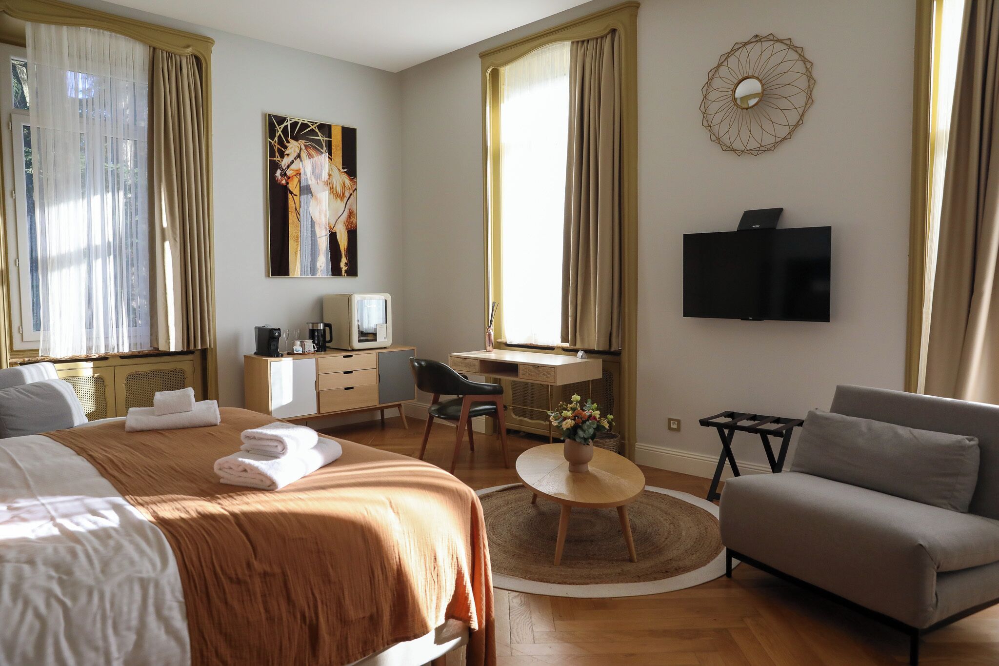 A hotel room with a bed, a desk with a computer, a TV, and a sofa.