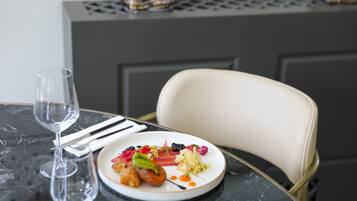 Ein Esstisch mit einem Teller Essen, einem Weinglas und einem Stuhl.
