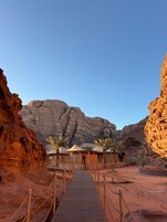 Un resort en el desierto con un muelle de madera que lleva a un edificio con palmeras.