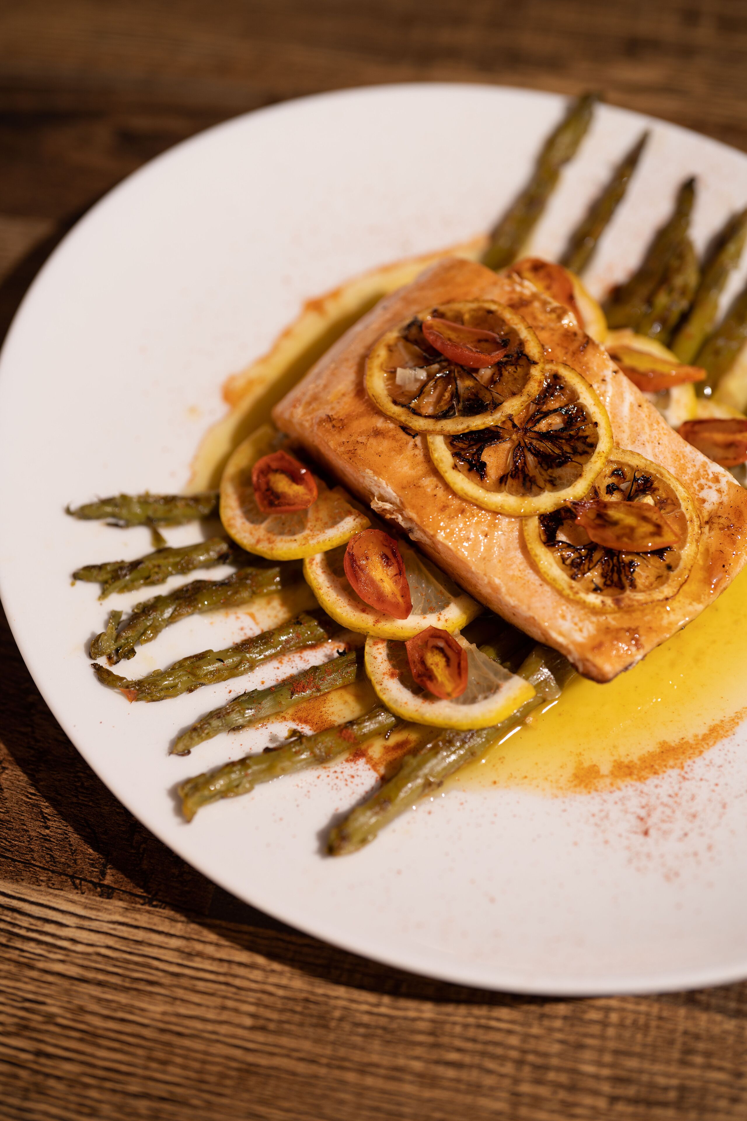 A plate with a salmon fillet, asparagus, and lemon slices.