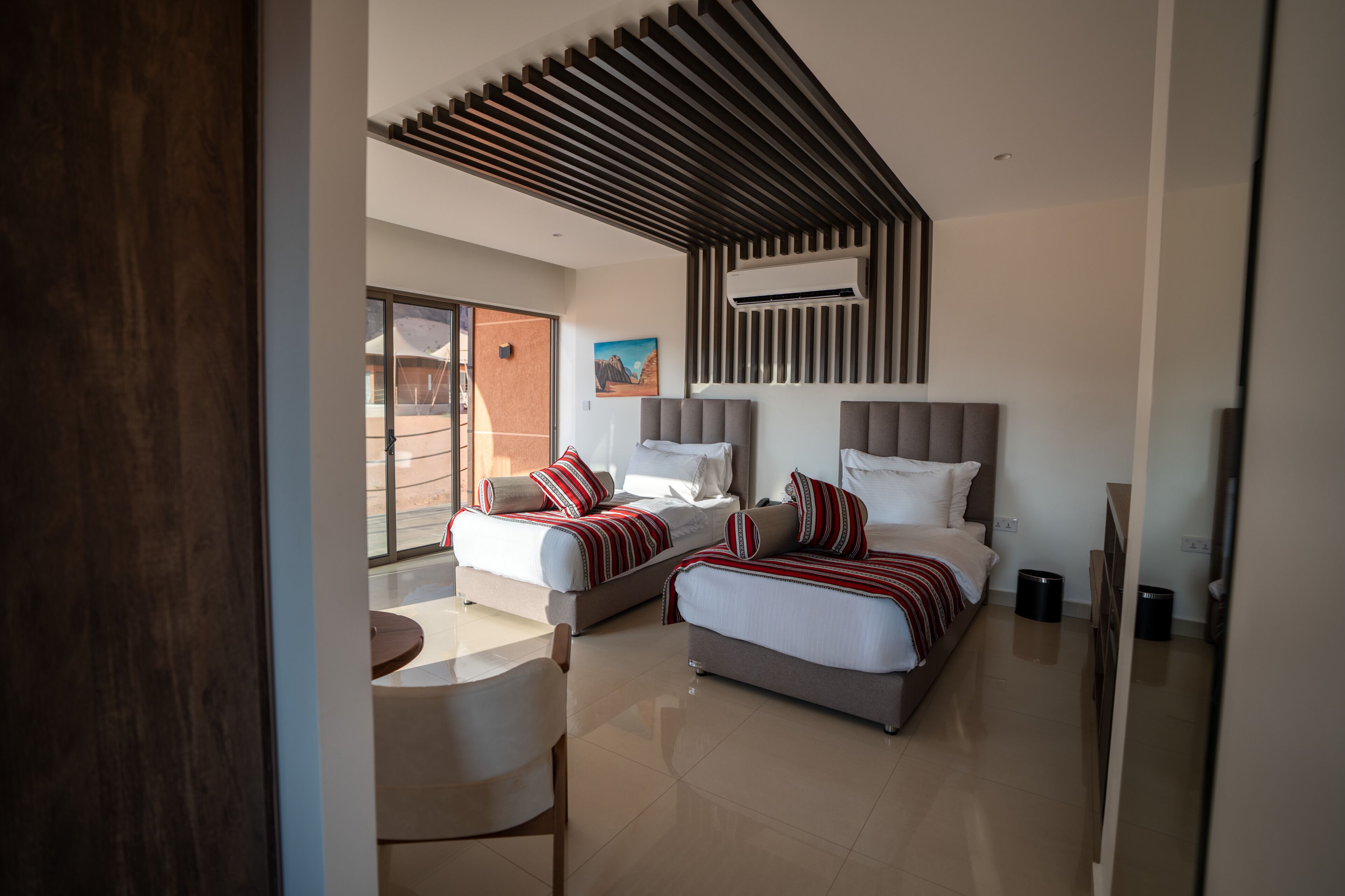 Una habitación de hotel moderna con dos camas, un área de comedor y un ventanal grande.