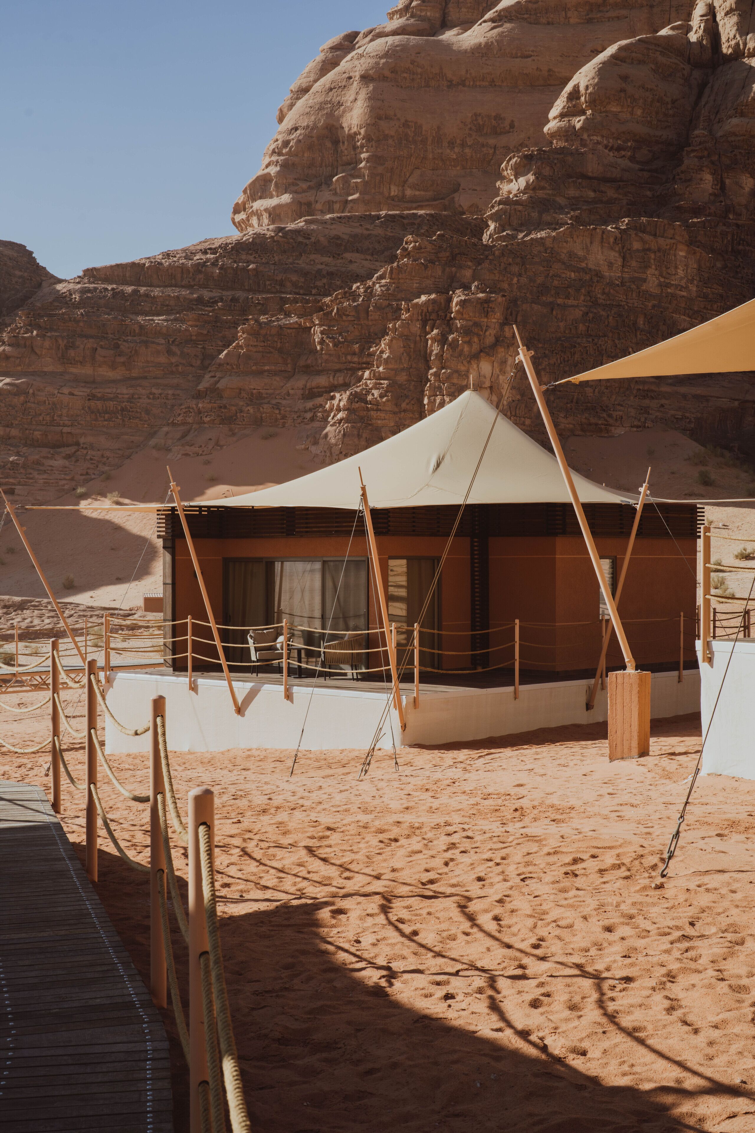 Una tienda de campaña en el desierto con terraza de madera y cuerdas de seguridad.