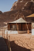 Una tienda de campaña en el desierto con terraza de madera y cuerdas de seguridad.