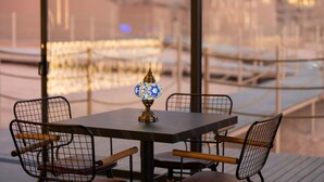 Un coin repas avec une table et des chaises, une lampe décorative et une vue dégagée grâce à de grandes fenêtres.