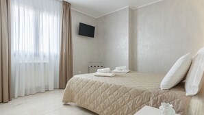 Ein Hotelzimmer mit einem Bett, einem Flachbildfernseher, einem Nachttisch und einer Vase.