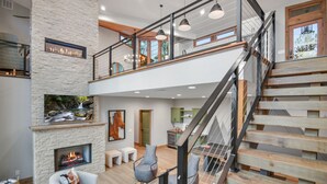 Un vaste espace de vie doté d’une cheminée, d’un escalier et offrant une vue sur l’extérieur.