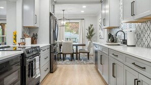 A modern kitchen with white cabinets, a central island, and a dining area with two chairs.