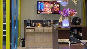 A modern kitchen with a flat-screen TV, pendant lights, and a coffee machine. - Chomm House (Bangkok)