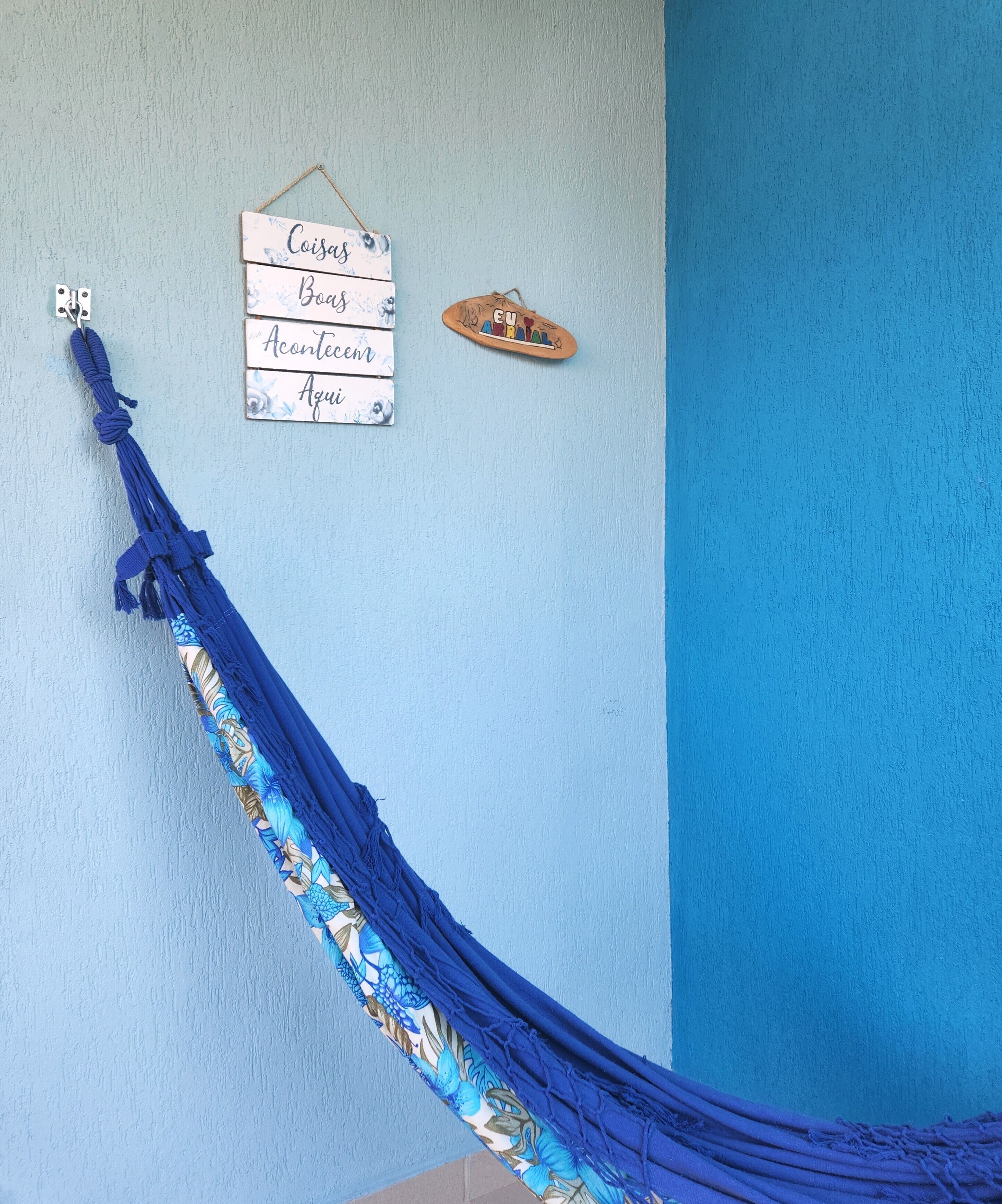 A blue hammock tied to a wall with a sign above it.