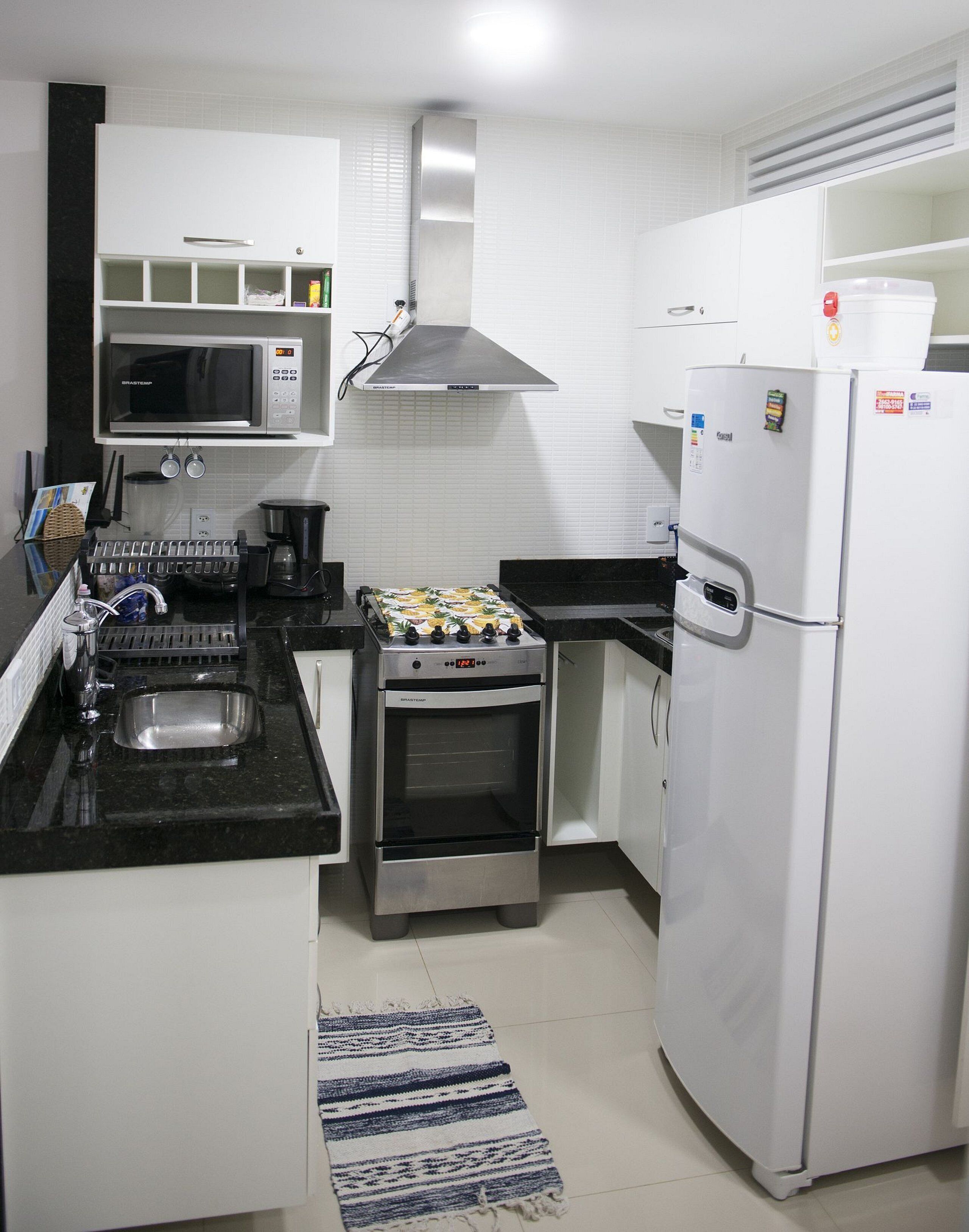 A compact kitchen with a microwave, oven, refrigerator, and a sink.