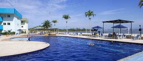 Una piscina al aire libre, sombrillas, sillones reclinables de piscina