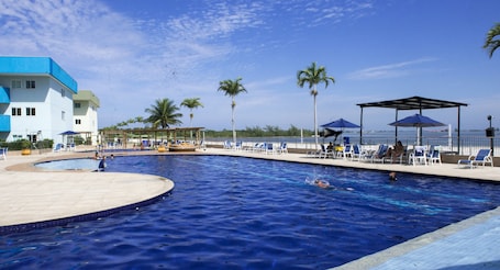 Una piscina al aire libre, sombrillas, sillones reclinables de piscina