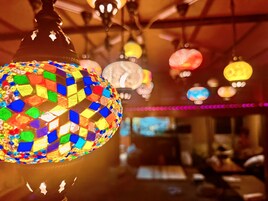 Una lampada colorata in mosaico appesa in una stanza calda, con sfondo sfocato.