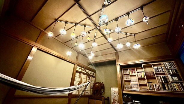 A room with a hammock, a ceiling light fixture, and a bookshelf filled with books. - Hotel1800 (Minamiuonuma)