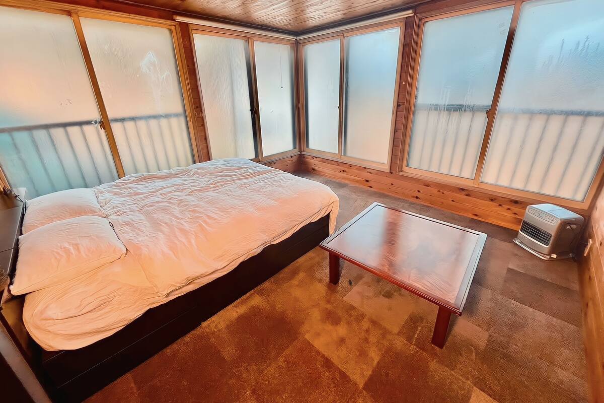A room with a bed, a bench, and a heater.