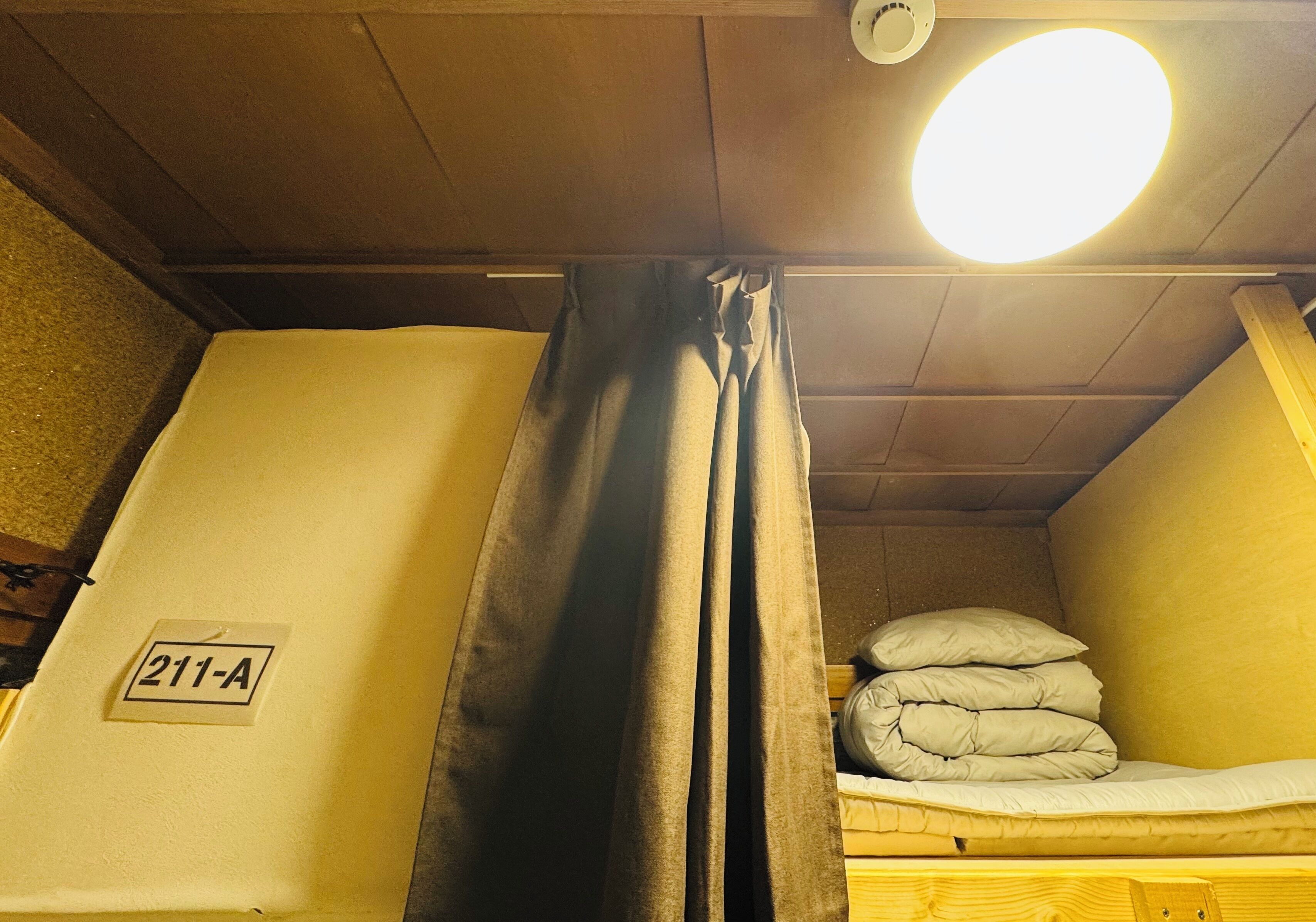 Una habitación con una cama, un cartel que indica '211-A' y una lámpara en el techo.